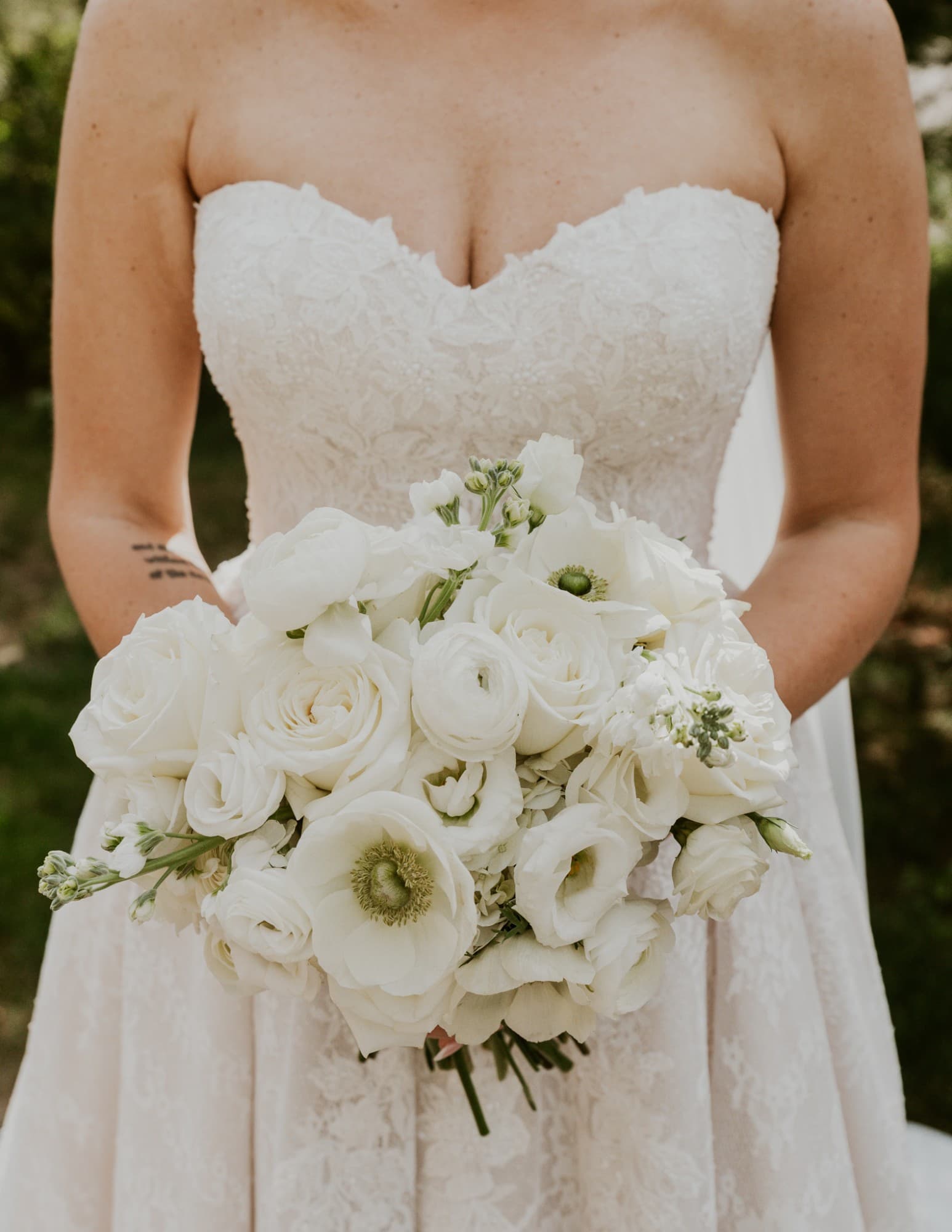 Close-up of a white bridal bouquet with roses, ranunculus, and anemones